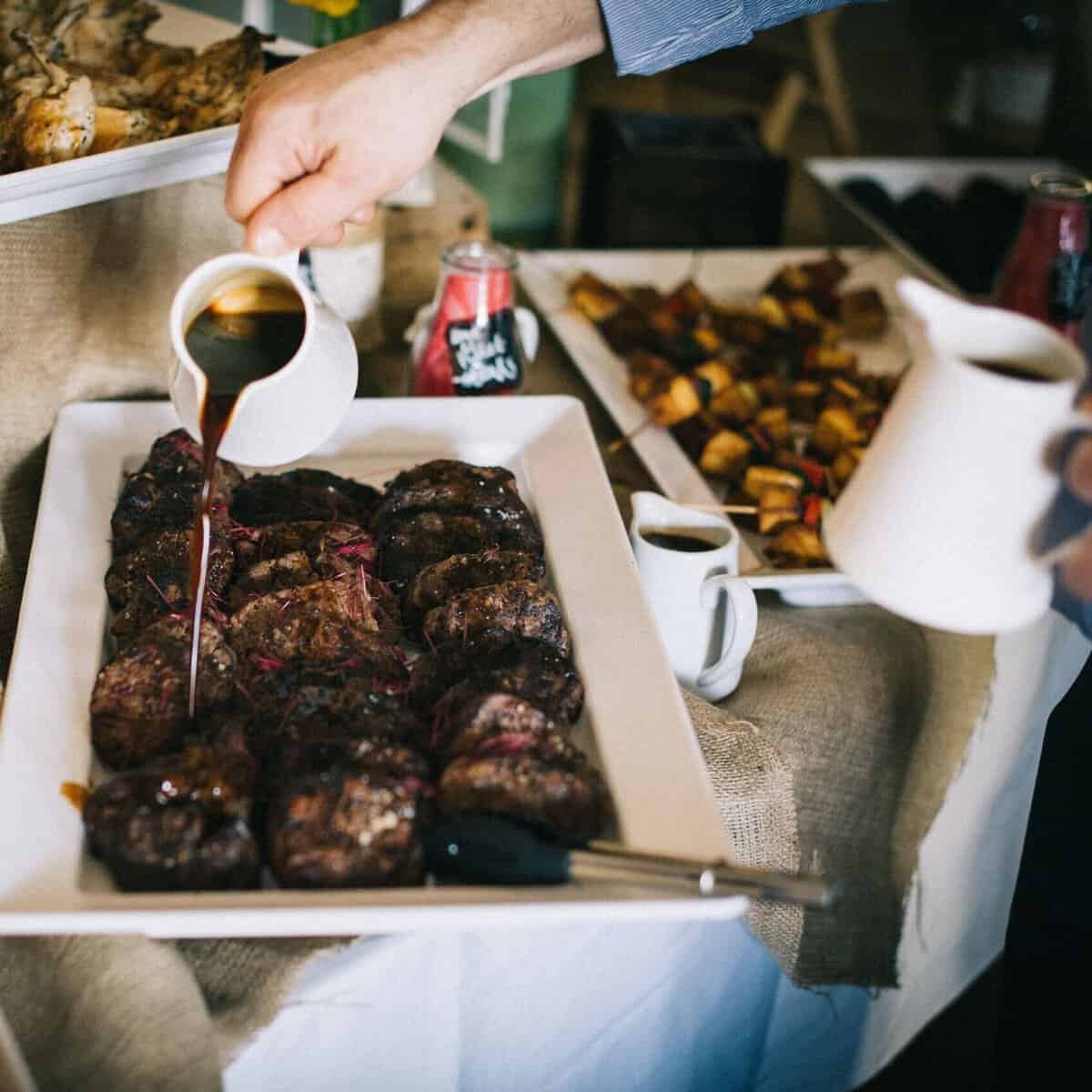 Grilled steaks being drizzled with sauce at a private chef event in Australia.